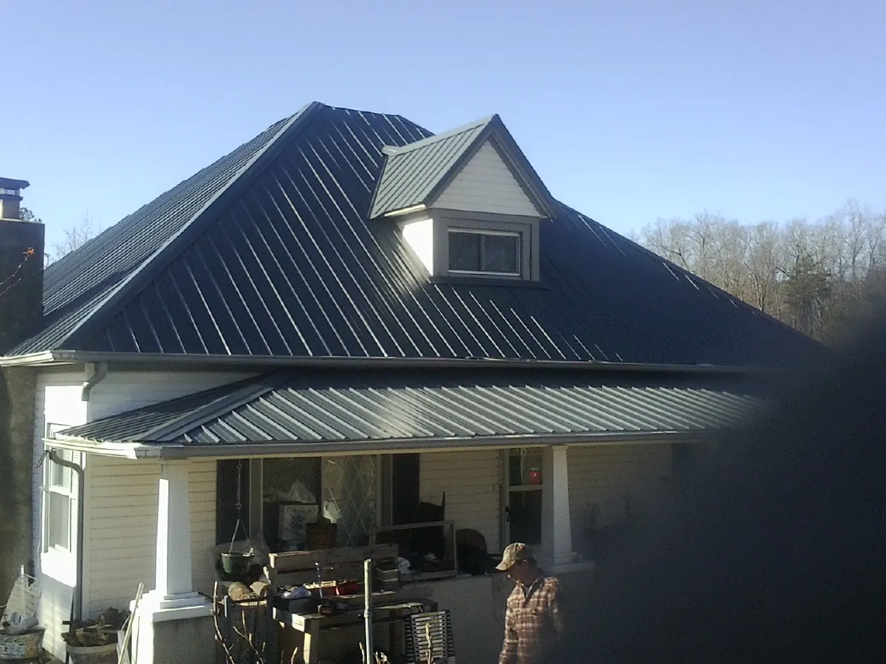 Dark blue standing seam metal roof with a dormer above a front porch in Omaha