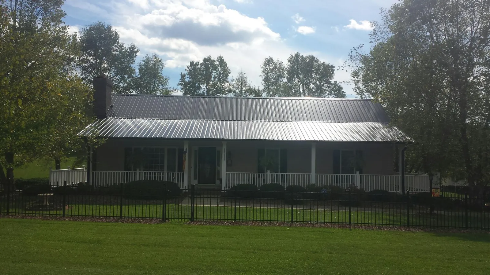 Gray metal roof on a brick ranch with a full width front porch — Gutter Guard Installation work by our crew in Omaha