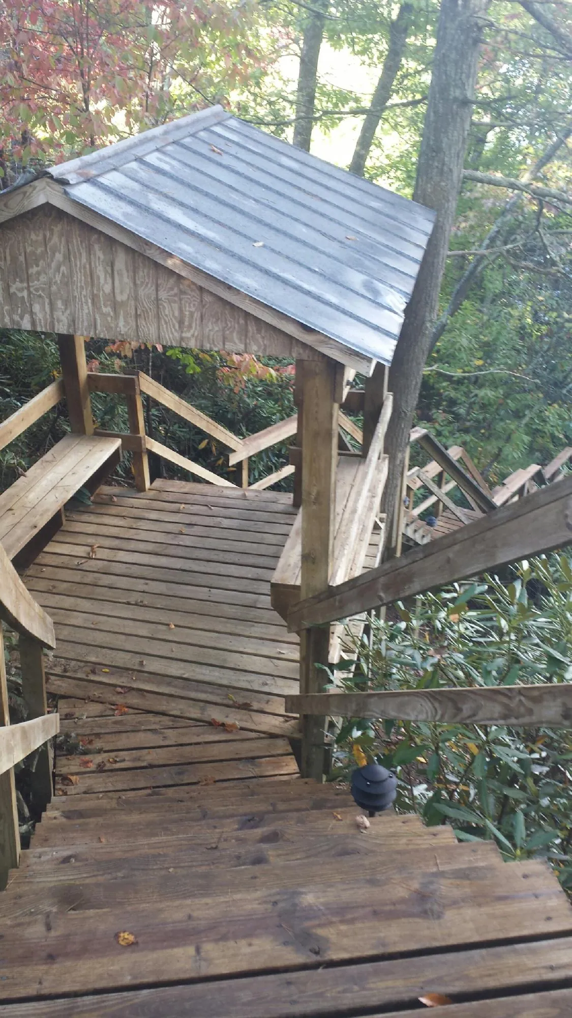 Metal roofed shelter over wooden steps on a wooded walkway — Skylight Repair & Installation work by our crew in Omaha