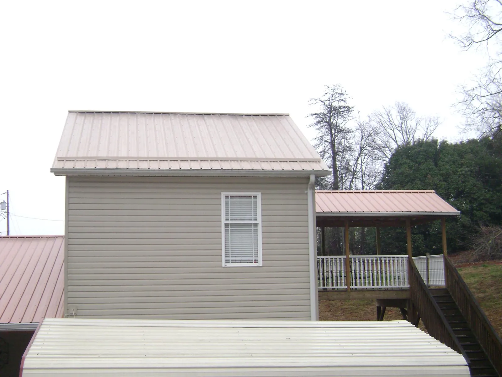 Tan metal roofs on a two story addition and attached porch, from a Roof Replacement job in Omaha