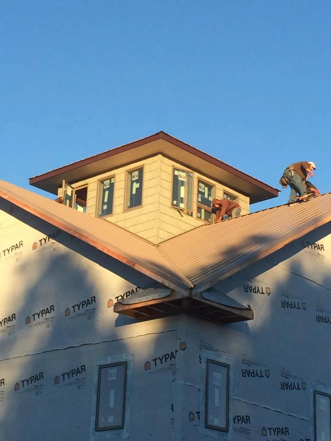 Roofers working around a rooftop cupola on a new metal roof at sunset — Roof Waterproofing in Omaha by Roofing Brothers